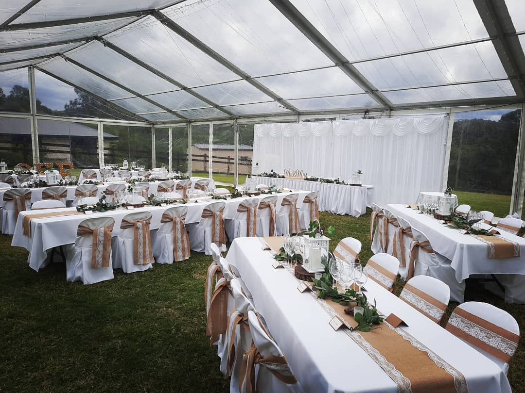 Tables and chairs set up inside a clear marquee
